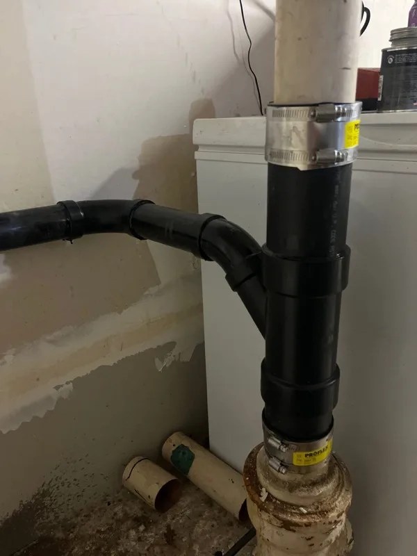 Cast iron drain stack and standpipe beside a laundry appliance