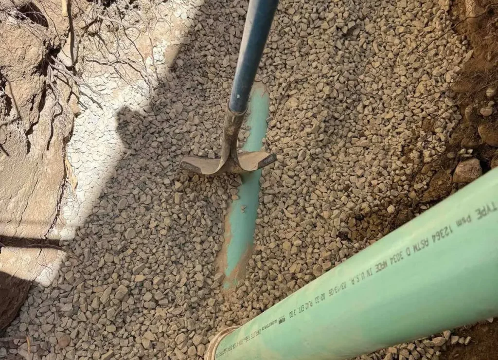 Green SDR sewer pipe bedded in gravel in an open excavation by Rare Breed Plumbing in Utah