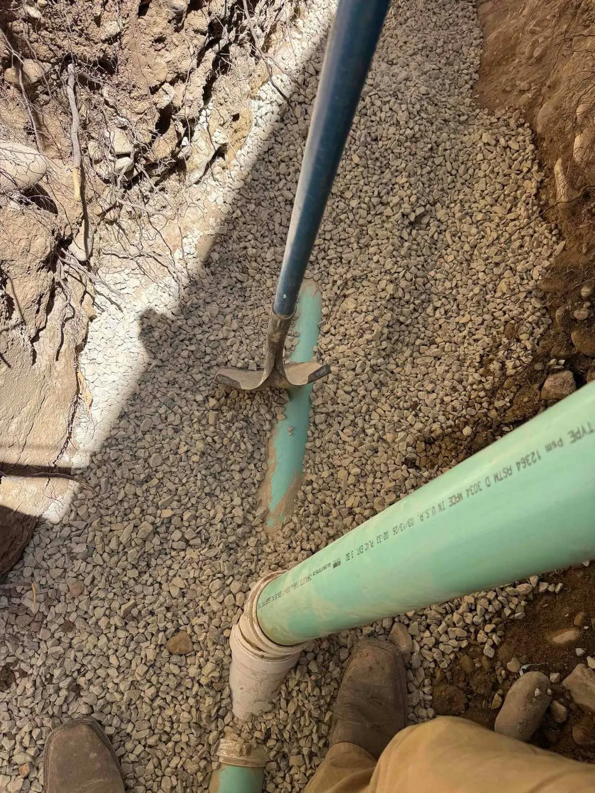 Green SDR sewer pipe bedded in gravel in an open excavation by Rare Breed Plumbing in Utah