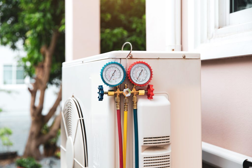 Rare Breed AC maintenance with manifold gauges on outdoor unit