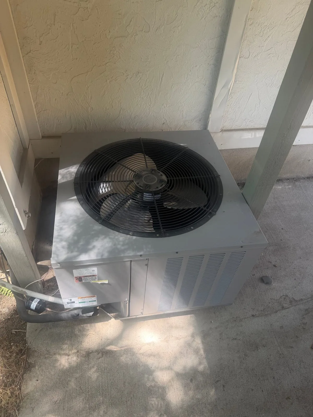 Outdoor air conditioning condenser unit beside a home