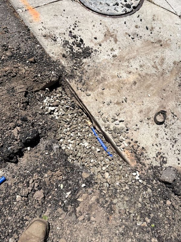Blue water line exposed in an asphalt cut in Utah