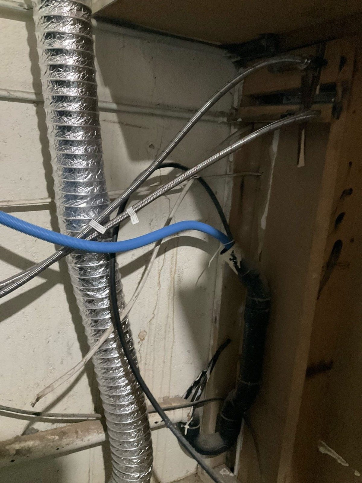 Flexible duct, blue PEX and conduit along a basement wall