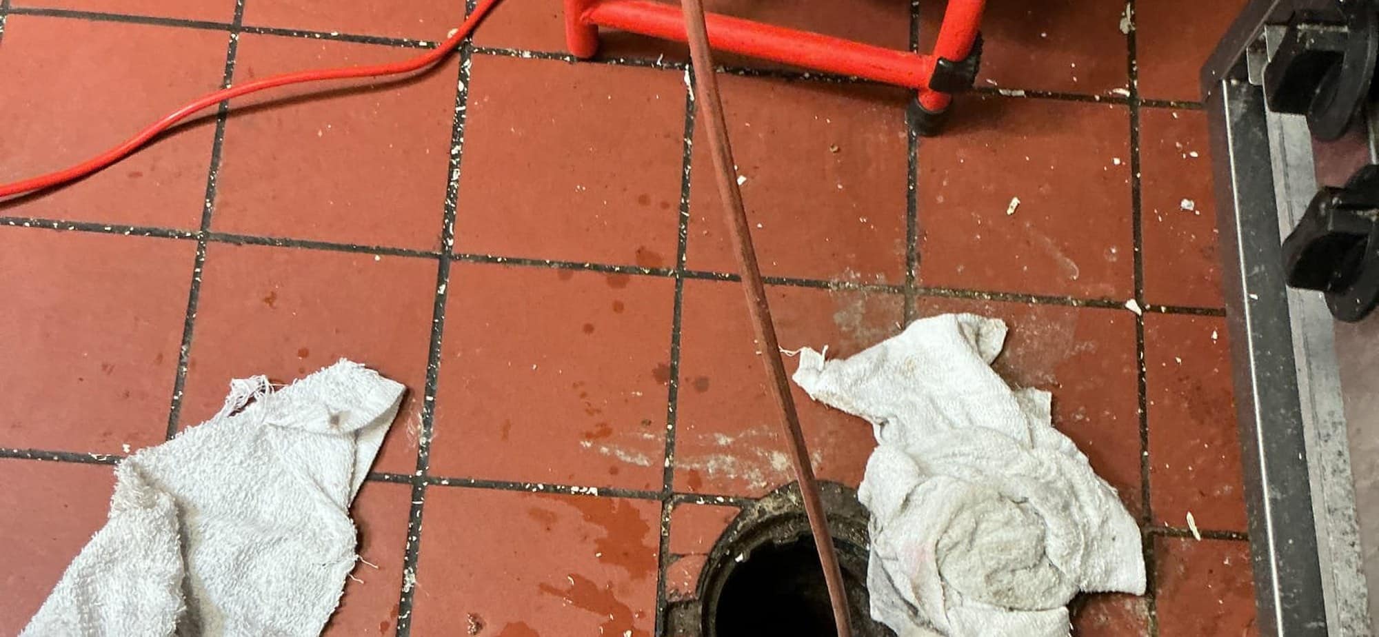 Hydro jetting hose fed from the jetter into an open floor cleanout to clear a main line