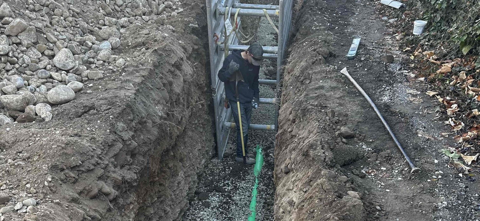 Technician working in a shored trench during a sewer and water main installation in Orem, Utah