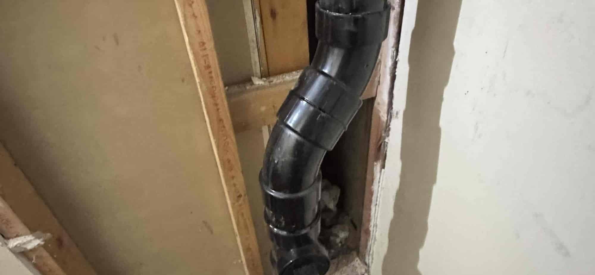 Cast iron drain stack exposed at a wall access point during a sewer line rehabilitation