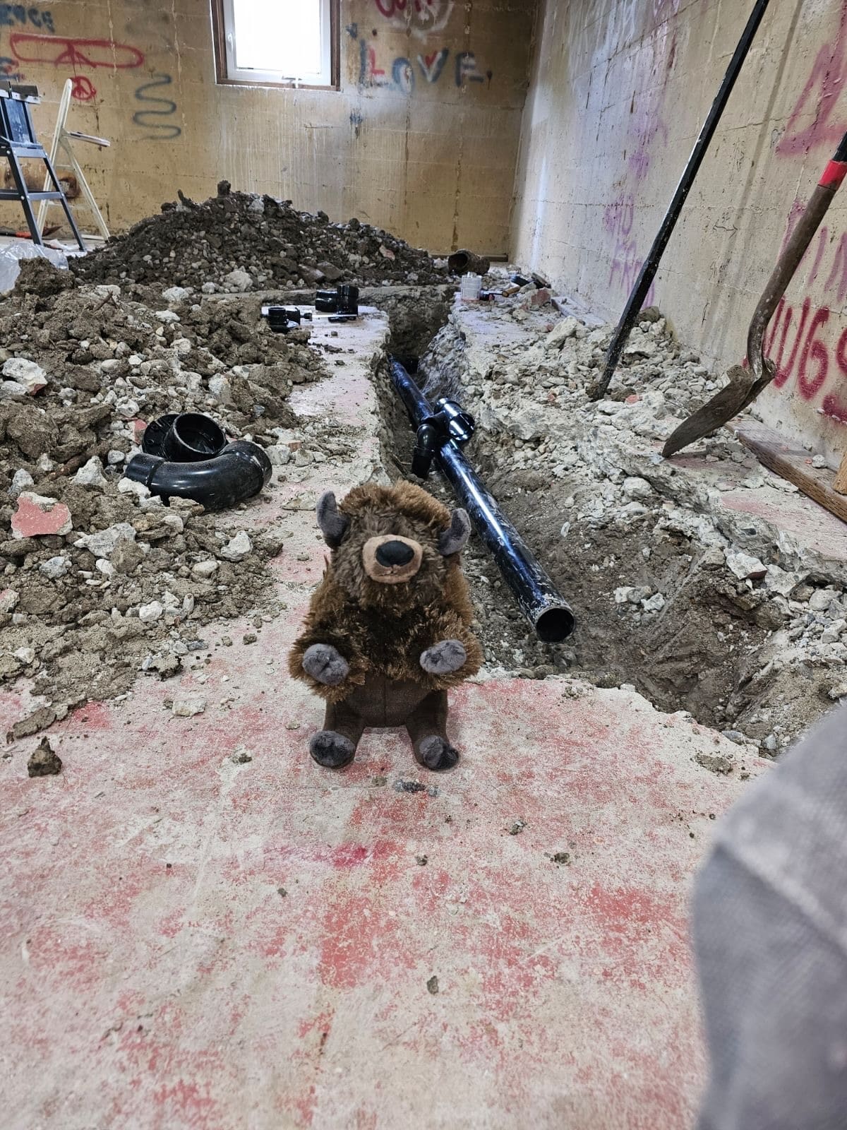 New sewer line laid in a trench cut through a basement concrete slab