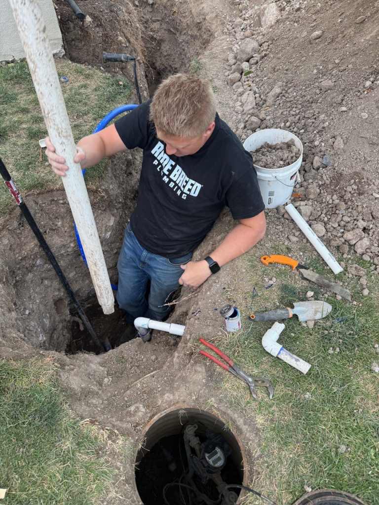 Rare Breed Plumbing technician repairing a water service line beside an open meter box